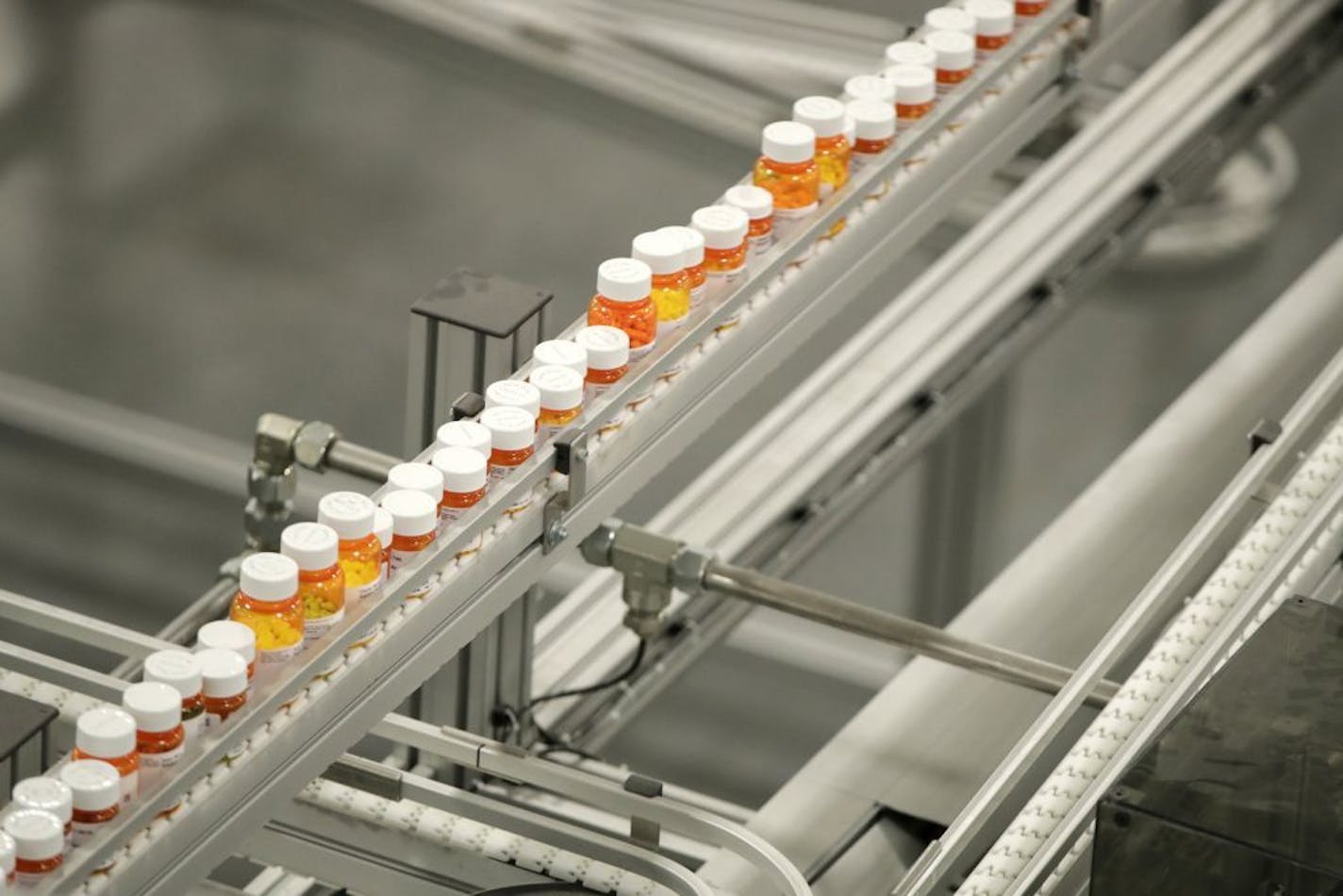 FILE- In this July 10, 2018, file photo bottles of medicine ride on a belt at a mail-in pharmacy warehouse in Florence, N.J. Drug companies are still raising prices for brand-name prescription medicines, just not as often or by as much as they used to, according to an Associated Press analysis.