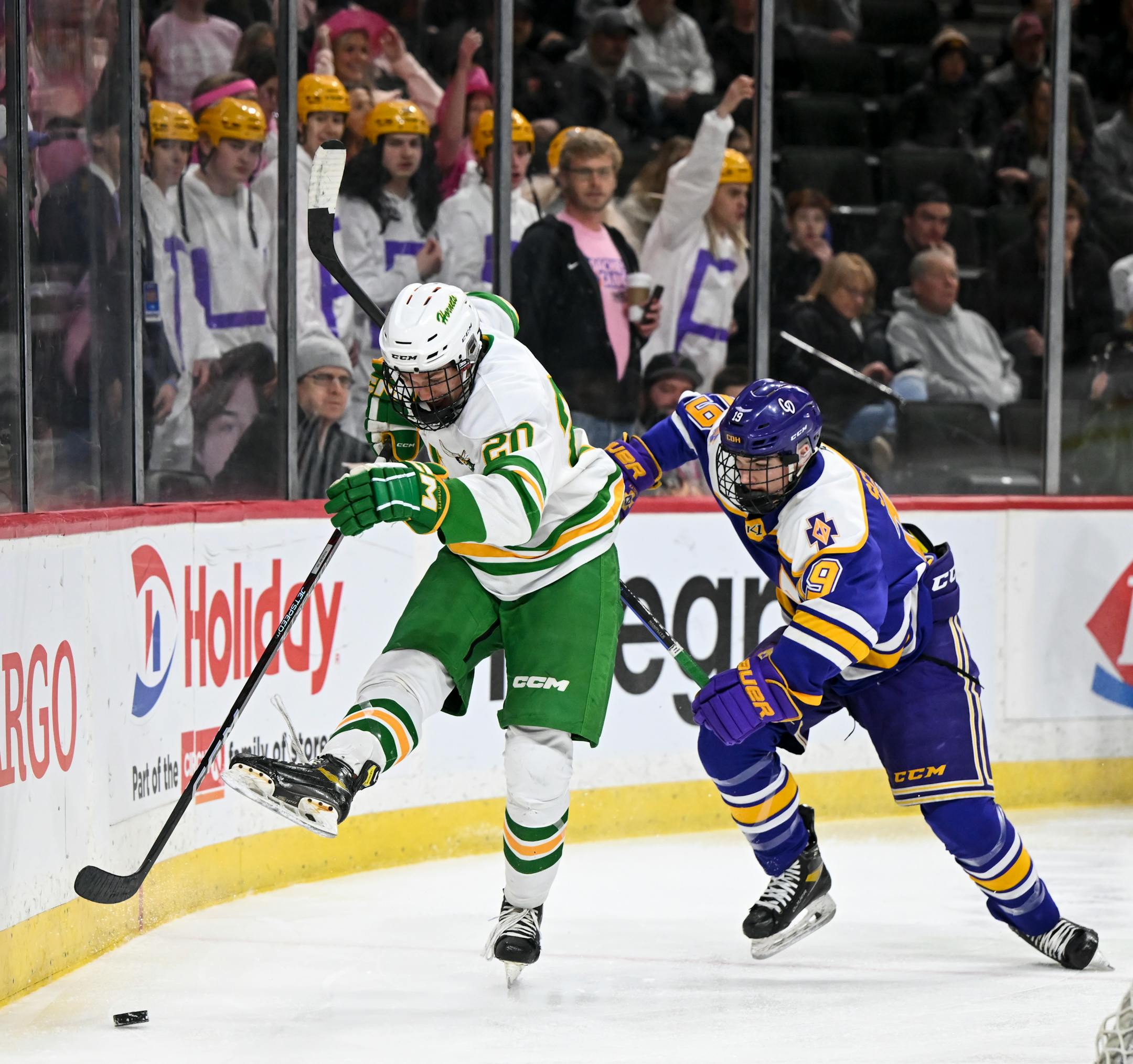 Edina defenseman Mikey Mason (20) kicks away the puck as he's challenged behind Edina's net by Cretin-Derham Hall forward Colin Scanlan (19) during the first period.