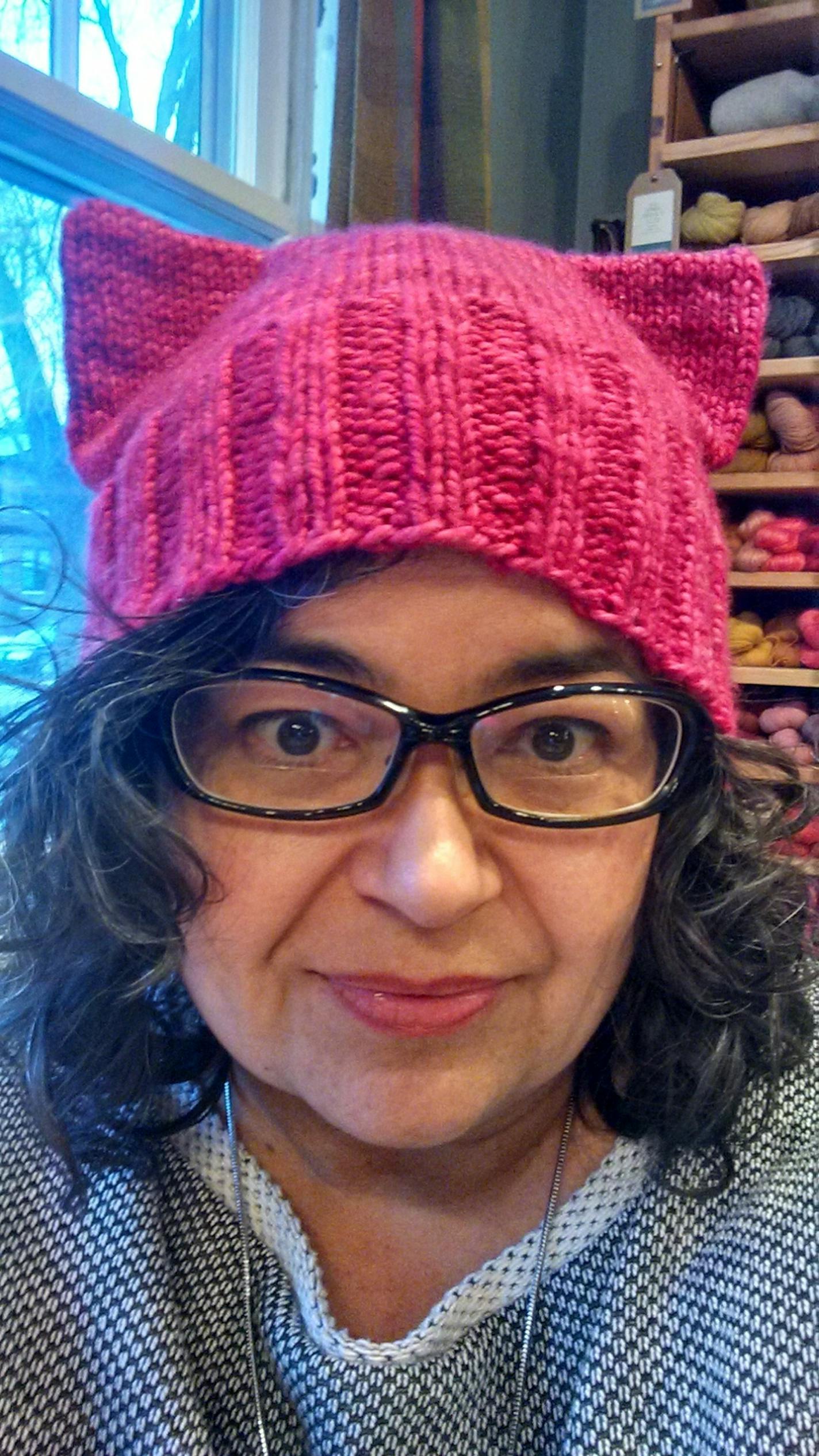 This January 2017 photo provided by Angie Paulson, shows Paulson, a knitter who works at The Yarnery shop in Saint Paul, Minn., as she displays one of the "pussy" hats she made as part of a call to action answered by thousands of knitters to supply marchers at the Women's March in Washington, D.C., on Jan. 21 with warm head gear and a way to show their solidarity for women's rights. (Angie Paulson via AP) ORG XMIT: MIN2017011616252392