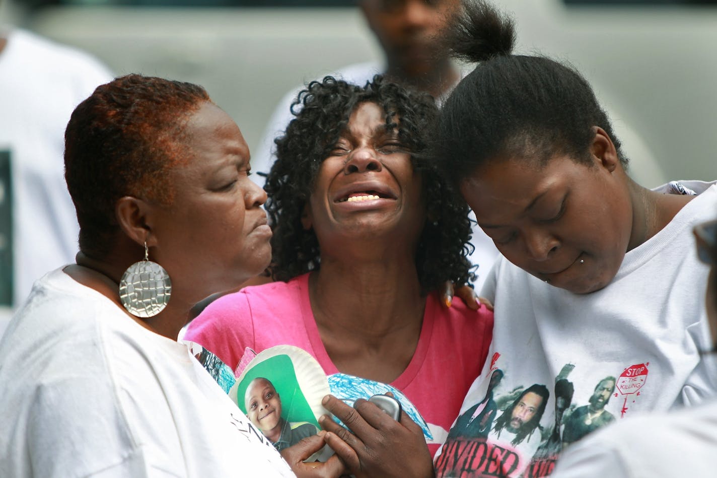 Rochelle Banks the grandmother of slain 5-year-old Ninzel Banks is comforted by family and other mothers who lost a chld to violence, as she clutches onto a picture of him on the 4500 block of Bryant Avenue North in Minneapolis, MN, June 26, 2012. (ELIZABETH FLORES/STAR TRIBUNE) ELIZABETH FLORES � eflores@startribune.com