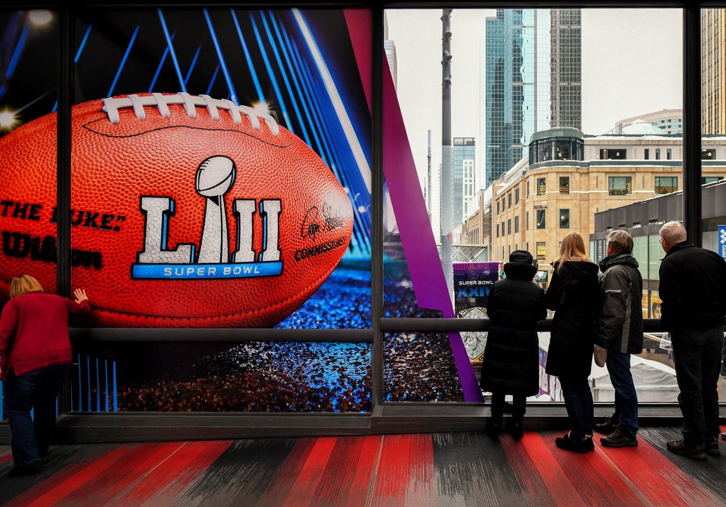 A skyway walker couldn't resist touching the Superbowl football banner over Nicollet Mall.