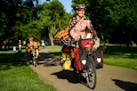 Sara Dykman, wearing a monarch butterfly cape, bike around Lake Nokomis with other festival goers Friday night. Dyman is cycling thousands of miles on