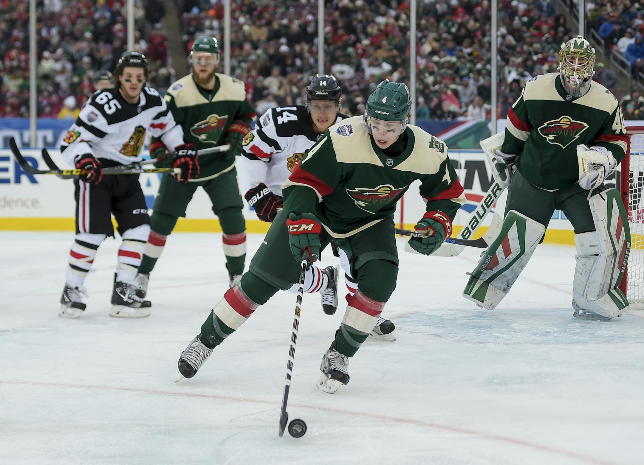 Minnesota Wild defensiveman Mike Reilly, center, clears the puck from in front of the goal while being pursued by Chicago Blackhawks right wing Richard Panik, third from left, and Minnesota Wild goalie Devan Dubnyk, right, looks on during the third period of the NHL Stadium Series hockey game at TCF Bank Stadium, Sunday, Feb. 21, 2016, in Minneapolis. The Wild win 6-1. (AP Photo/Craig Lassig)