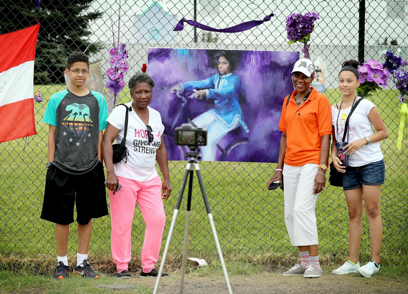 The Woodard family poses for a photo, taken by a camera on tripod, at the memorial for Prince at Paisley Park. From left is Christien, 14, of Columbus, Ohio, his grandmother Pat of Erie, Pa., his great-aunt Frankie of Brooklyn Park, and sister Dominique, 12, of Columbus, Ohio. ] (Leila Navidi/Star Tribune) leila.navidi@startribune.com BACKGROUND INFORMATION: At Paisley Park in Chanhassen on July 4, 2016. More than two months after Prince's untimely death at Paisley Park, what is the scene at his