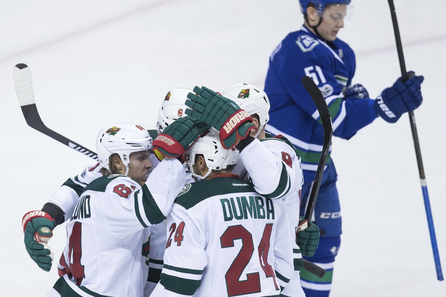 Minnesota Wild's Mikael Granlund, of Finland; Marco Scandella; Matt Dumba; and Mikko Koivu, of Finland, from left, celebrate Granlund's second goal as Vancouver Canucks' Troy Stecher, back right, skates to the bench during the second period of an NHL hockey game Saturday, Feb. 4, 2017, in Vancouver, British Columbia. (Darry Dyck/The Canadian Press via AP)