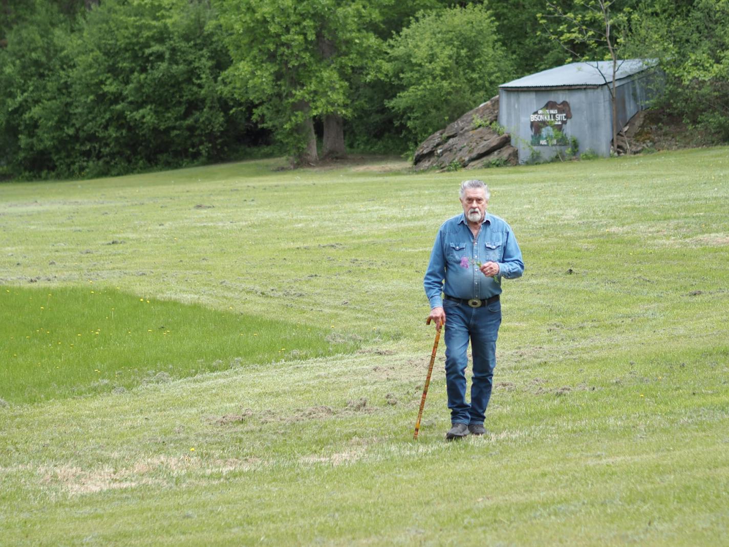 LeRoy Peterson holds a wild flower in his pasture.