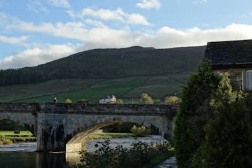 A high Yorkshire fell rises behind the River Wharfe and the five-arch bridge, a well-known landmark in Burnsall. Photo by Dave Hage * dave.hage@startr