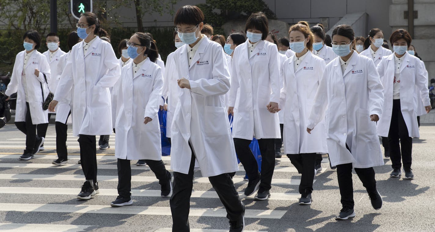 Medical workers from Beijing walk near a park during a day off as the city of Wuhan slowly loosens up ahead of a lifting of the two month long lockdown in central China's Hubei province on Sunday, April 5, 2020. The quarantine in the city which is the epicenter of China's coronavirus outbreak is to be formally lifted on Wednesday. (AP Photo/Ng Han Guan)