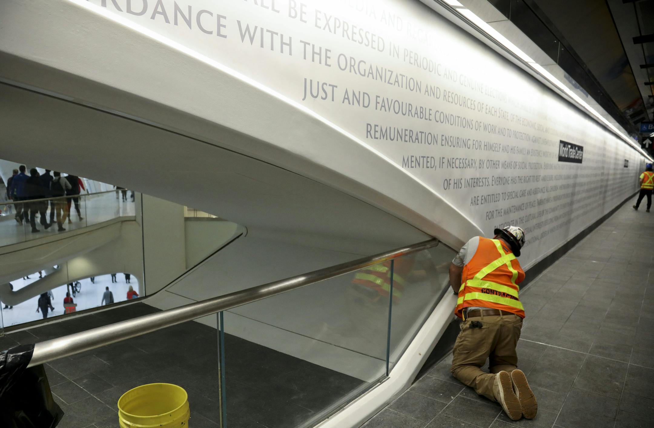 A contractor works near the main entrance of the rebuilt WTC Cortlandt station at the MTA's Oculus transportation hub and shopping center, Monday Sept. 10, 2018, in New York. The station, which features text from the Declaration of Independence and the United Nations Universal Declaration of Human Rights along its walls, reopened after it was destroyed in the World Trade Center attack 17 years ago. (AP Photo/Bebeto Matthews)