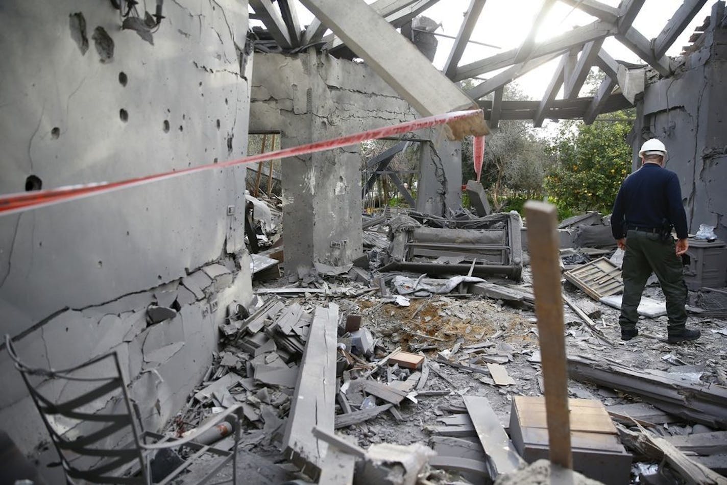 A police officer inspects the damage to a house hit by a rocket in Mishmeret, central Israel, Monday, March 25, 2019. An early morning rocket from the Gaza Strip struck a house in central Israel on Monday, wounding six people, including one moderately, an Israeli rescue service said, in an eruption of violence that could set off another round of violence shortly before the Israeli election.