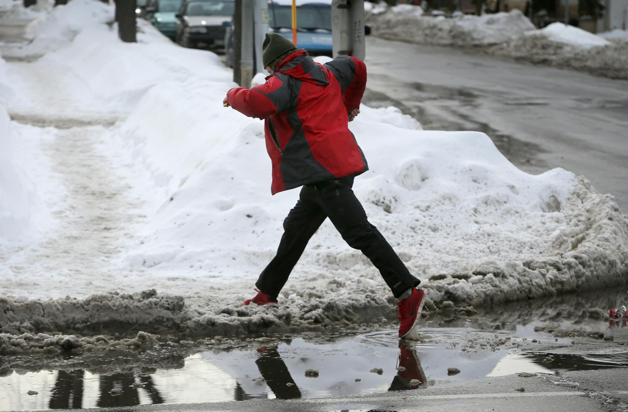 John Rasmussen of Minneapolis leaps a puddle of fresh snow melt along Lagoon Ave. and Irving Ave. S. Tuesday in Minneapolis,