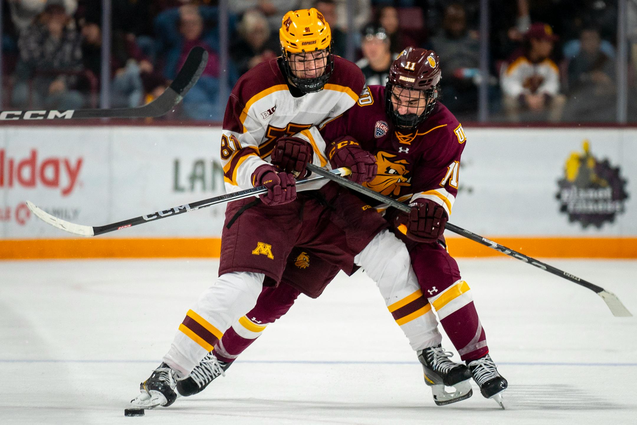 Minnesota forward Jimmy Snuggerud (81) and Duluth Center Cole Spicer (11) wrestle for the puck.
