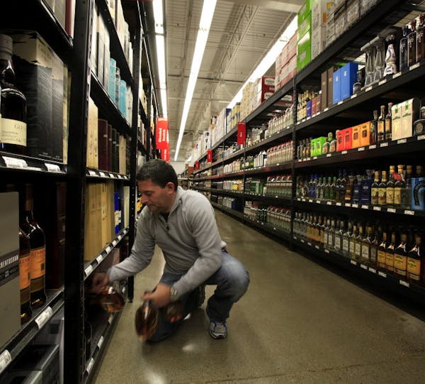 FILE PHOTO. Owner John Wolf stocks the shelves at Liquor Boy in St. Louis Park in November 2013. He first looked at opening a liquor store in Minneton