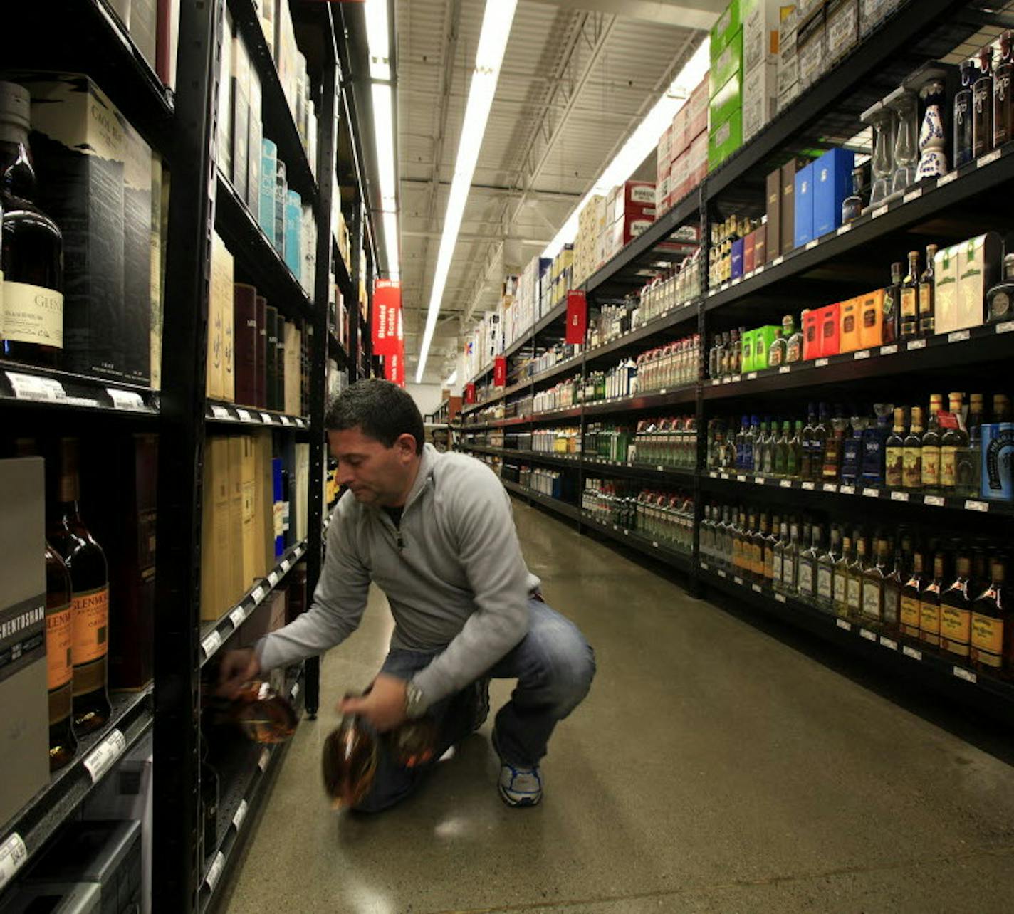 FILE PHOTO. Owner John Wolf stocks the shelves at Liquor Boy in St. Louis Park in November 2013. He first looked at opening a liquor store in Minnetonka, but withdrew his application after the city changed its liquor license policy and opted for St. Louis Park instead.