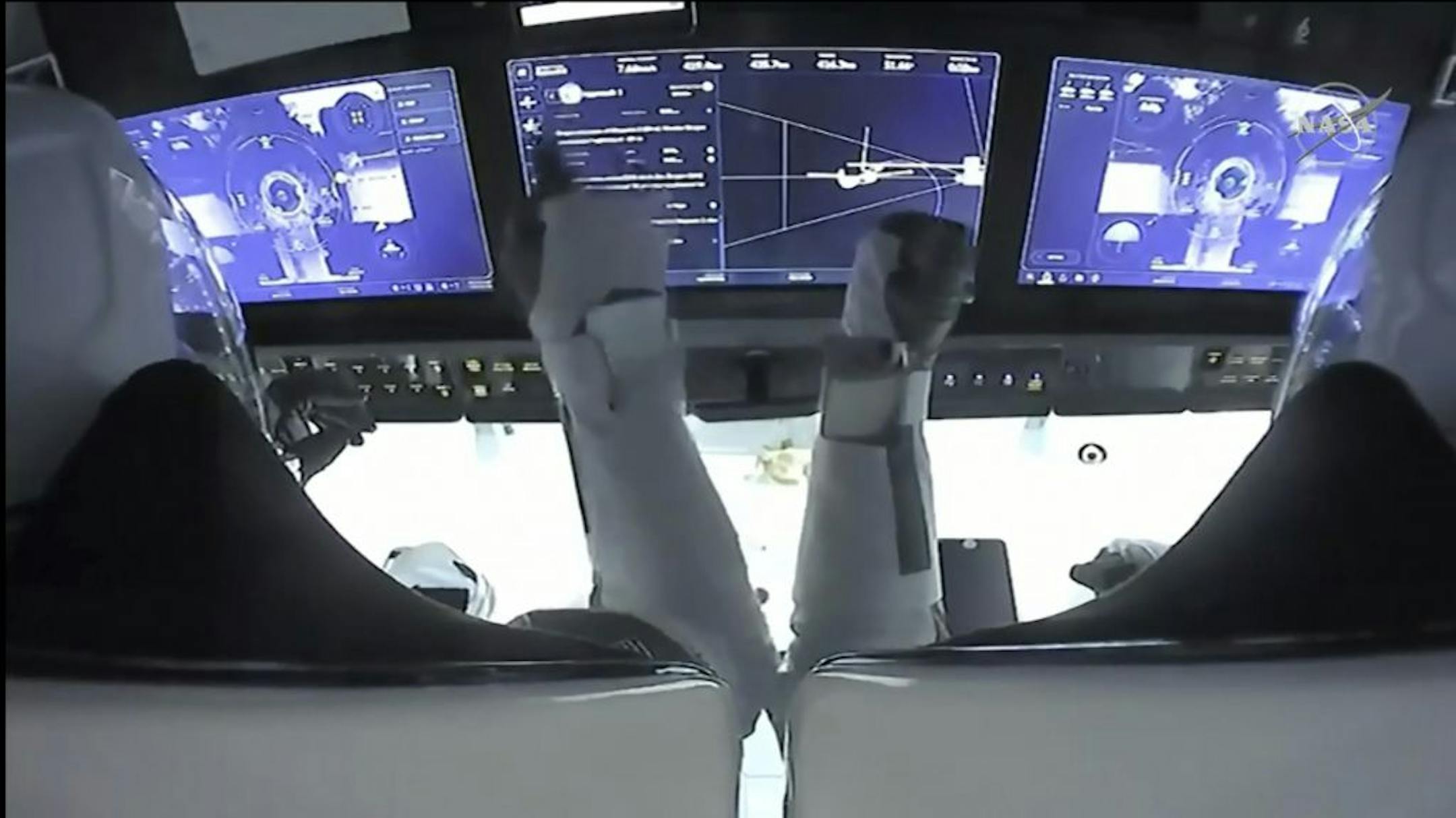 In this frame grab from NASA TV, astronauts Mike Hopkins, left, and Victor Glover monitor controls aboard SpaceX Dragon as the capsule approaches the International Space Station, late Monday, Nov. 16, 2020.