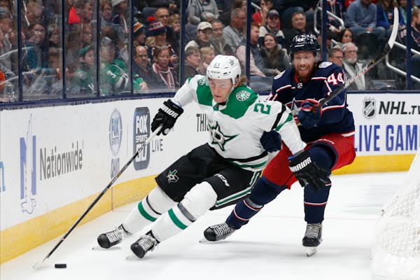 Dallas Stars' Roope Hintz, left, of Finland, carries the puck behind the net as Columbus Blue Jackets' Vladislav Gavrikov, of Russia, defends during t