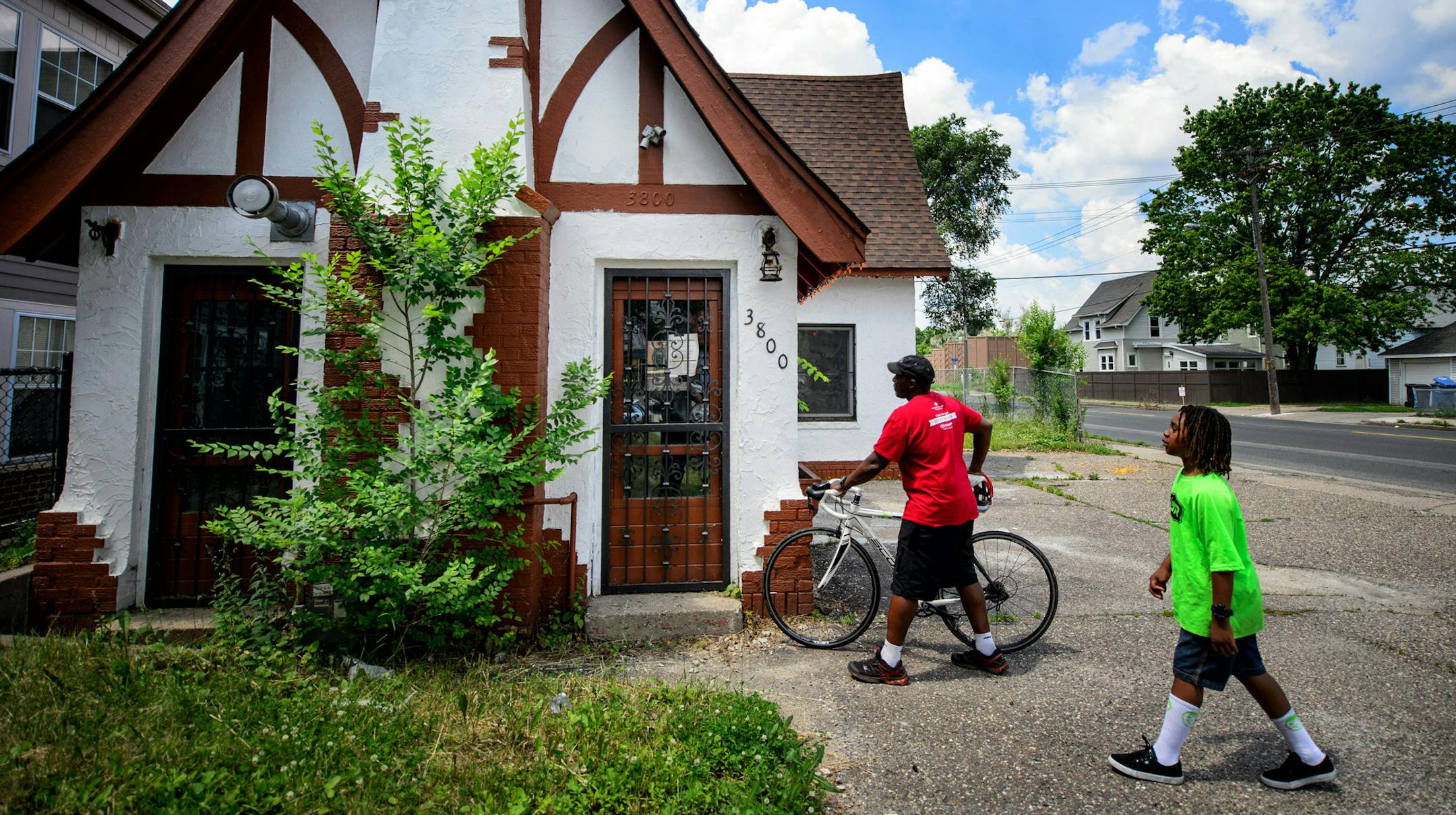 Anthony Theba and his son Aten-Wa Theba at the building Anthony hopes to turn into a bike shop. ] GLEN STUBBE * gstubbe@startribune.com Friday, June 26, 2015 Anthony Theba is planning to open a bike shop to address racial equity issues in cycling in an old filling station near 35W on E. 38th Street. Across the street, a food co-op is betting with a multi-milion-dollar building that the historically black but rapidly Latinizing area wil have an appetite for healthy food. Across 38th, the longtime