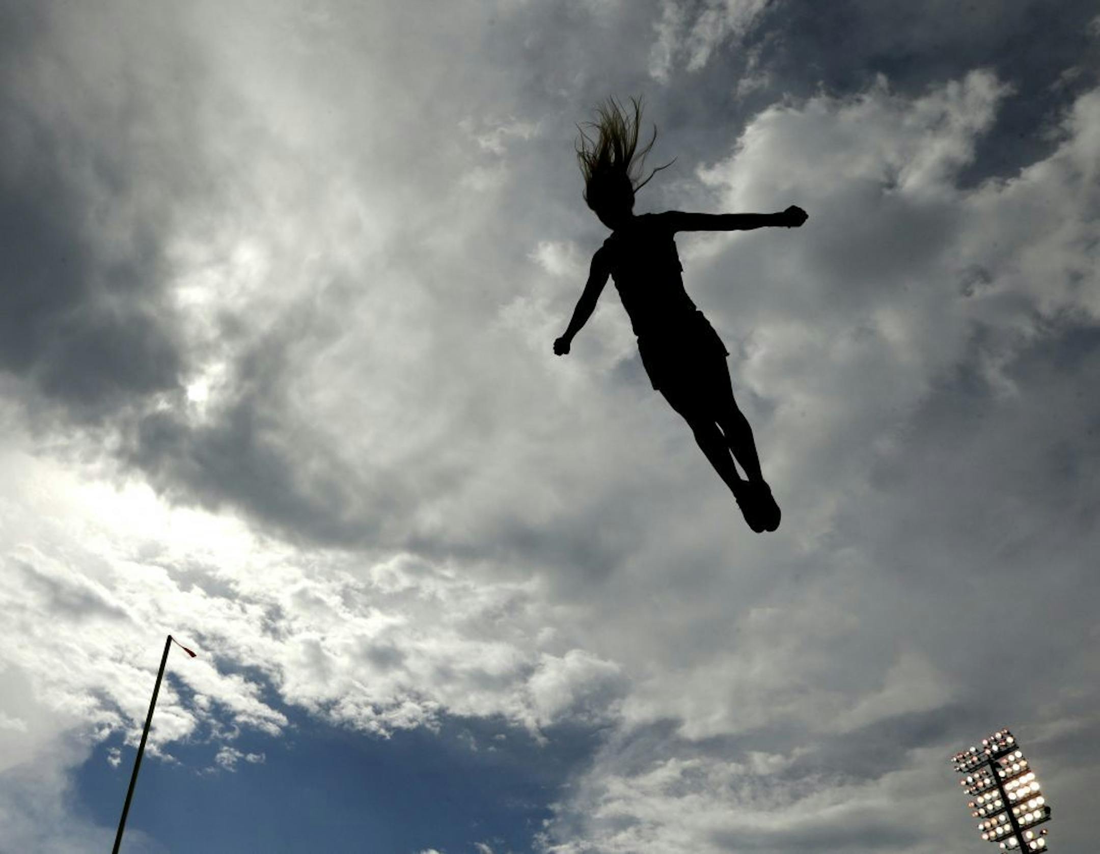 A Kansas cheerleader is silhouetted against storm clouds during the first half of an NCAA college football game against Central Michigan Saturday, Sept. 20, 2014, in Lawrence, Kan.