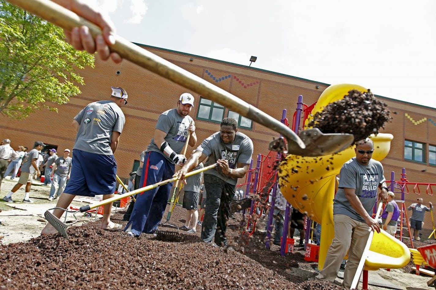 Minnesota Vikings Pierce Burton, left, and Antonio Richardson, center, joined other players, coaches, and school staff to help build a playground at Lucy Craft Laney School during the annual Vikings Playground Build, Wednesday, June 4, 2014 in Minneapolis, MN.