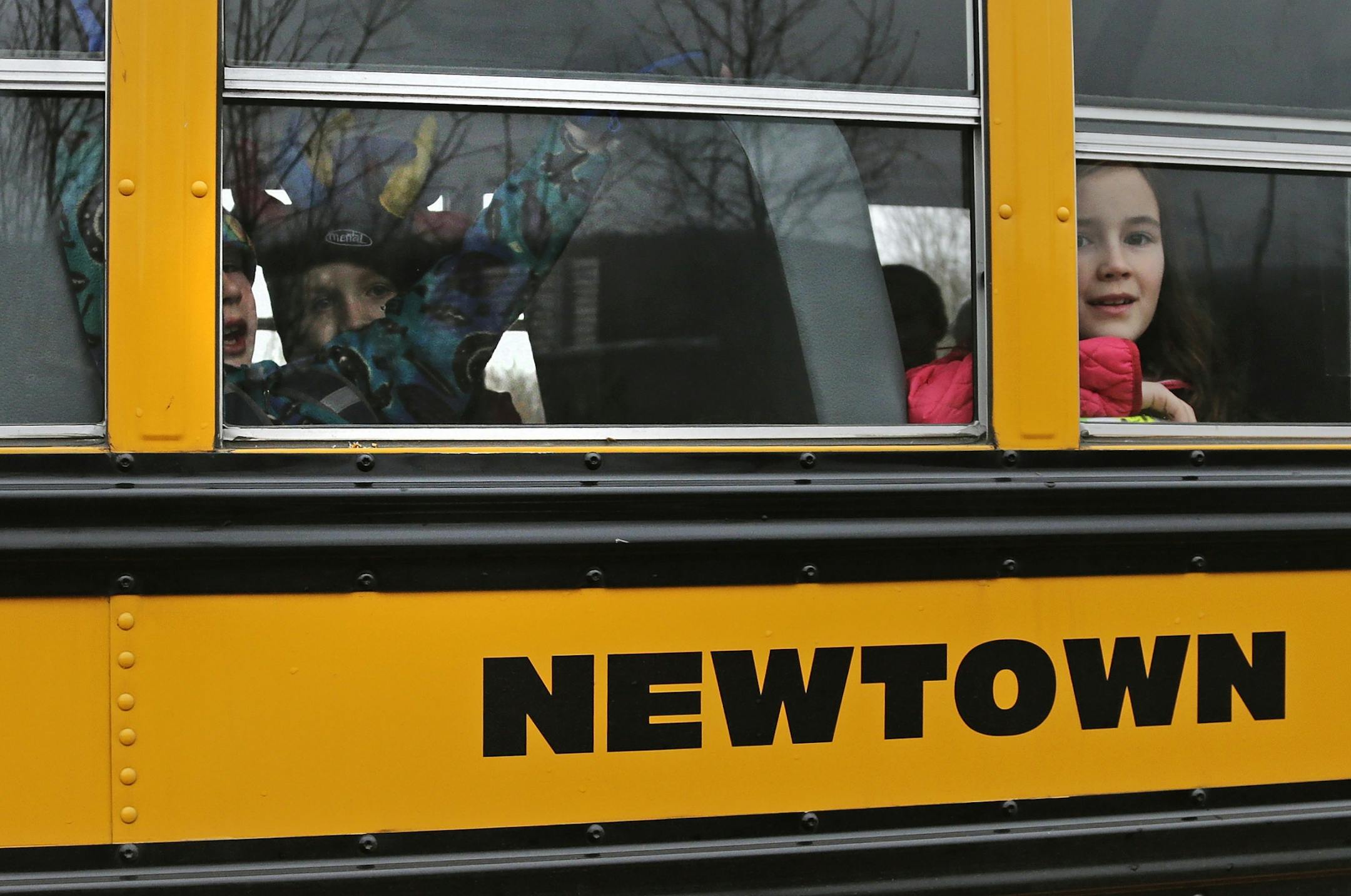 Schoolchildren look out the window of their bus as they head back to school in Newtown, Conn., Tuesday, Dec. 18, 2012. Classes resume Tuesday for Newtown schools except those at Sandy Hook. Buses ferrying students to schools were festooned with large green and white ribbons on the front grills, the colors of Sandy Hook. At Newtown High School, students in sweatshirts and jackets, many wearing headphones, betrayed mixed emotions. Adam Lanza walked into Sandy Hook Elementary School in Newtown, Fri