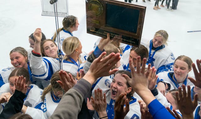 Minnetonka players rush the glass near the student section while forward Grace Sadura holds up their trophy after defeating Holy Family 4-0.