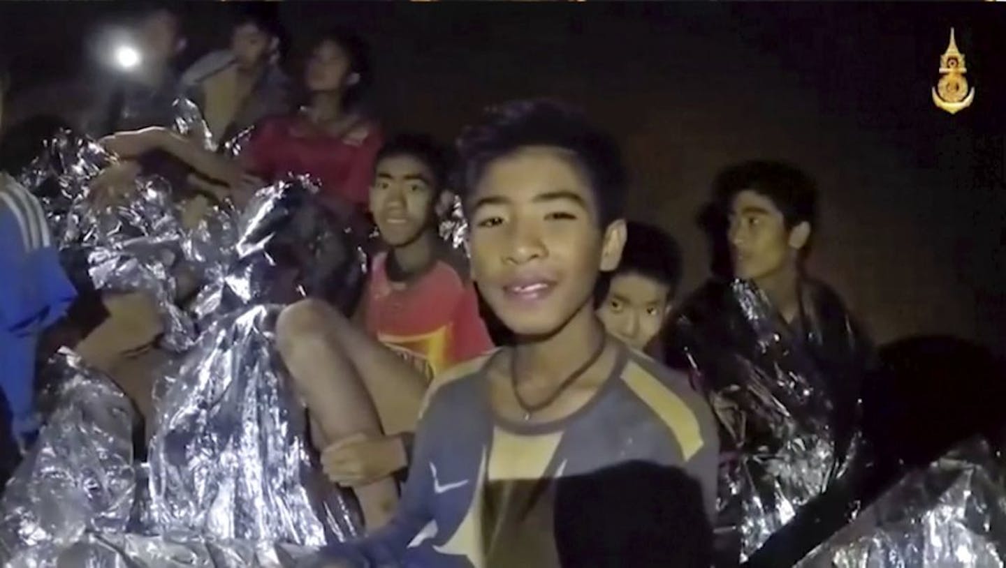 FILE - In this July 3, 2018, file image taken from video provided by the Royal Thai Navy Facebook Page, the boys smile as Thai Navy SEAL medic help injured children inside a cave in Mae Sai, northern Thailand. The group was discovered July 2 after 10 days totally cut off from the outside world, and while they are for the most physically healthy, experts say the ordeal has likely taken a mental toll that could worsen the longer the situation lasts.