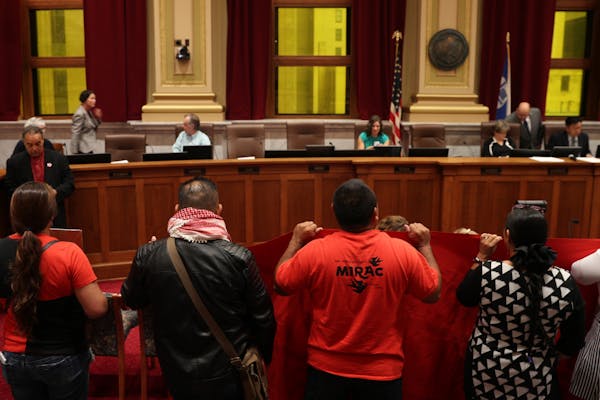 Immigrant rights activists chanted and held signs at the start of the Minneapolis City Council meeting to draw attention to a 13-point "Sanctuary Plat