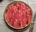 A round rhubarb tart with pieces of roasted rhubarb arranged in a decorative pattern.