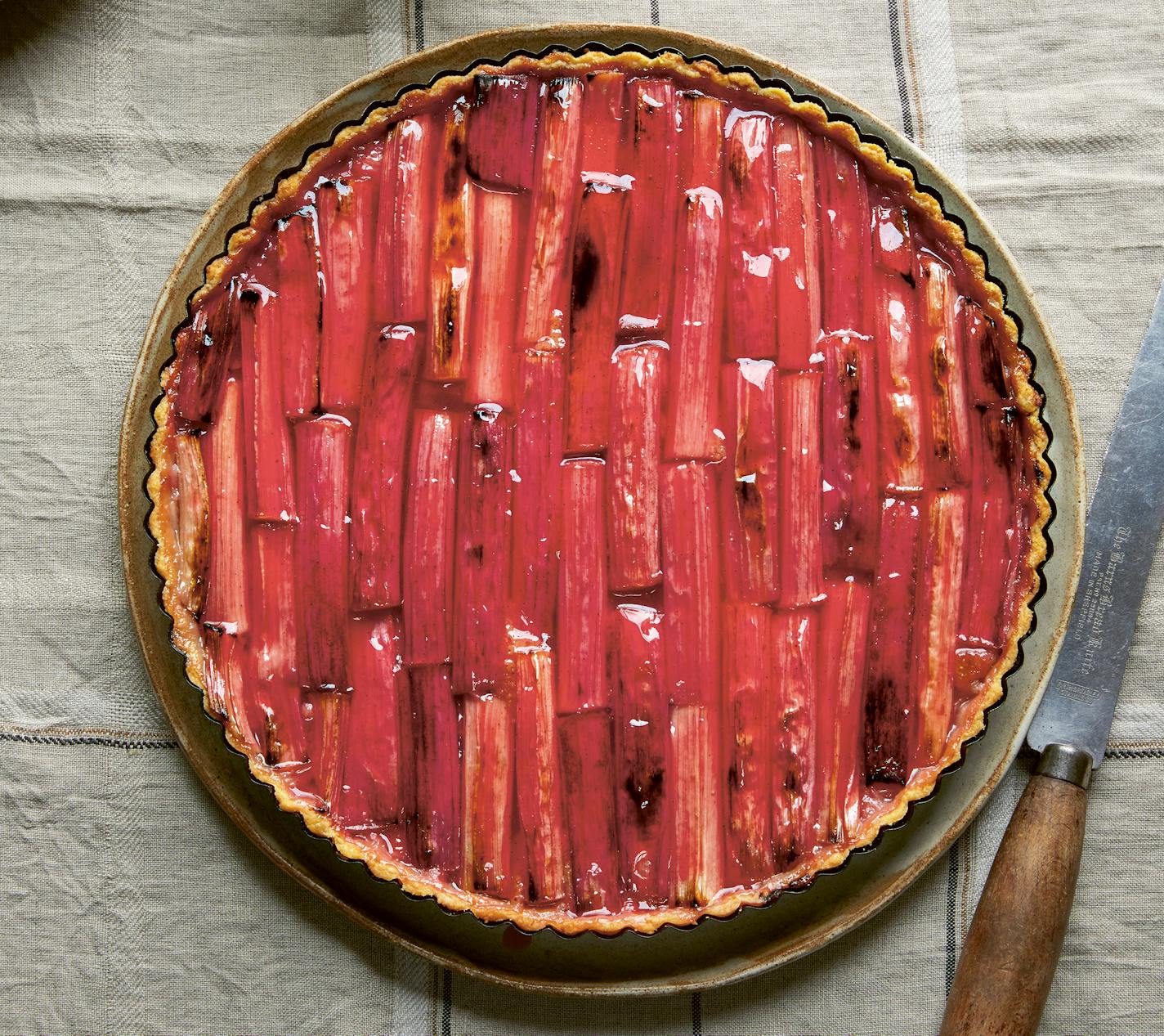 A round rhubarb tart with pieces of roasted rhubarb arranged in a decorative pattern.