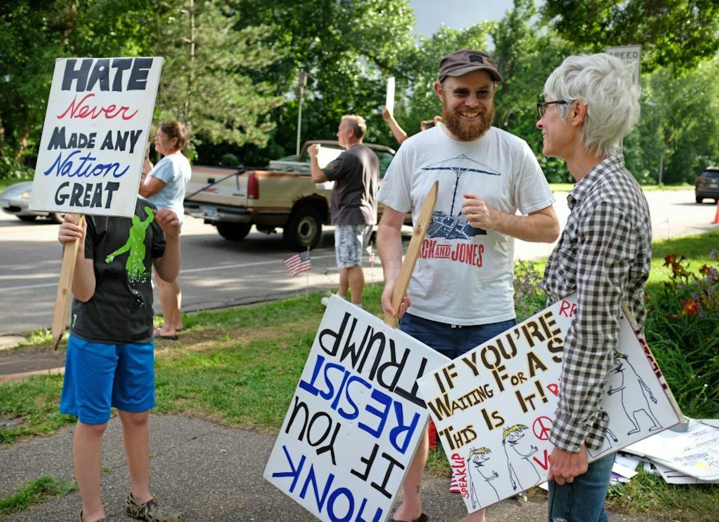 Bryce Tache, a member of a neighborhood political group, recently began standing on a corner in Pearl Park (Portland Ave. and Diamond Lake Rd. nightly from 6-7 pm holding signs protesting Trump policies. Here he speaks with Kim Hyvarinen who came to hold signs. At left is son Elias Tache-Donaldson.