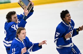 Minnetonka forward Ashton Schultz (11), defenseman Liam Hupka (17) and forward Javon Moore (22) celebrate their 2-1 double overtime victory against Ch