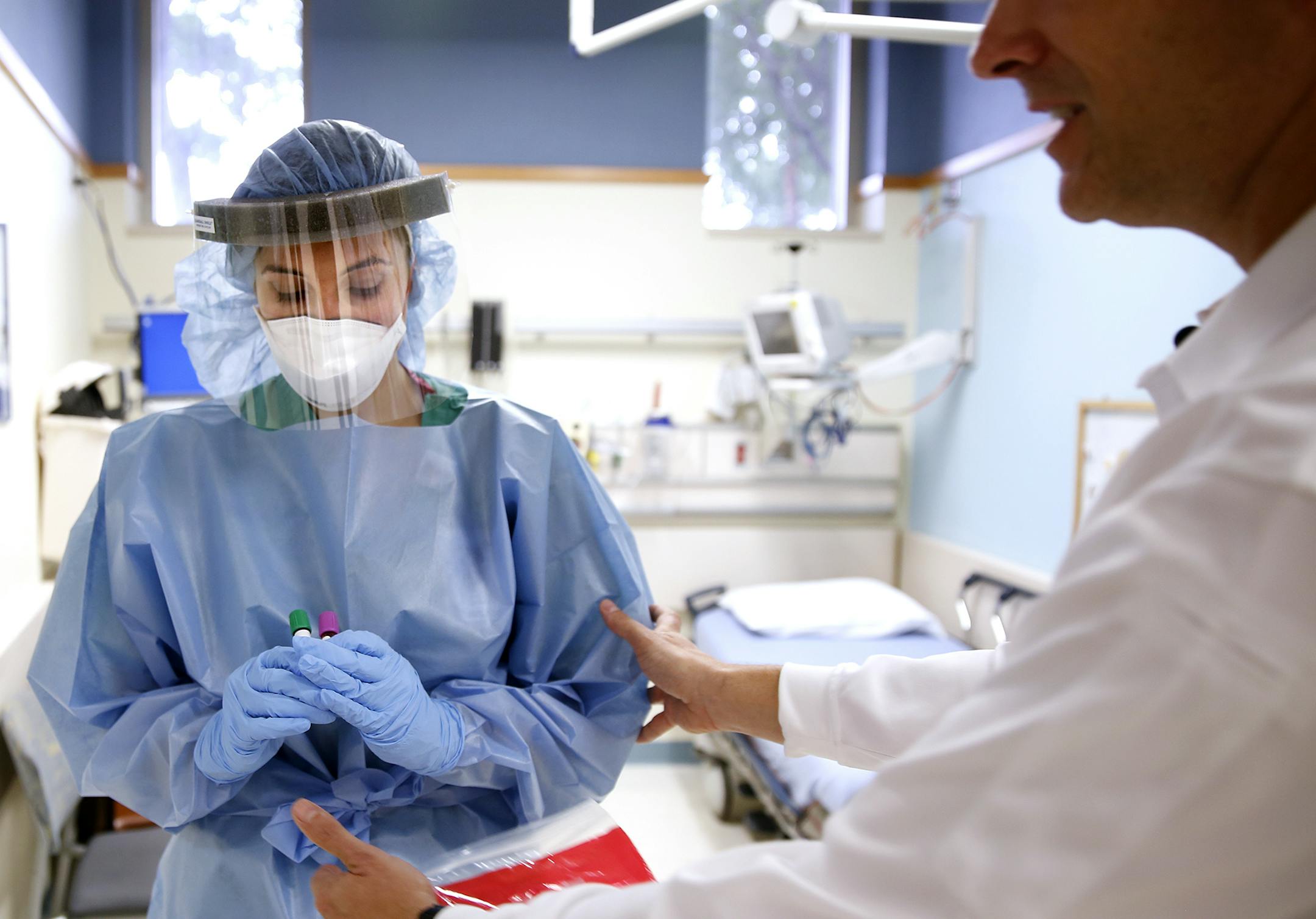 Dr. John Hick, Emergency Physician and Medical Director of Hennepin EMS, right, directs Dr. Rochelle Zarzar, a first year resident at the Hennepin County Medical Center emergency department, to pose wearing the Personal Protective Equipment (PPE) that would be used in care for patients with Ebola symptoms at the Hennepin County Medical Center during a press conference.