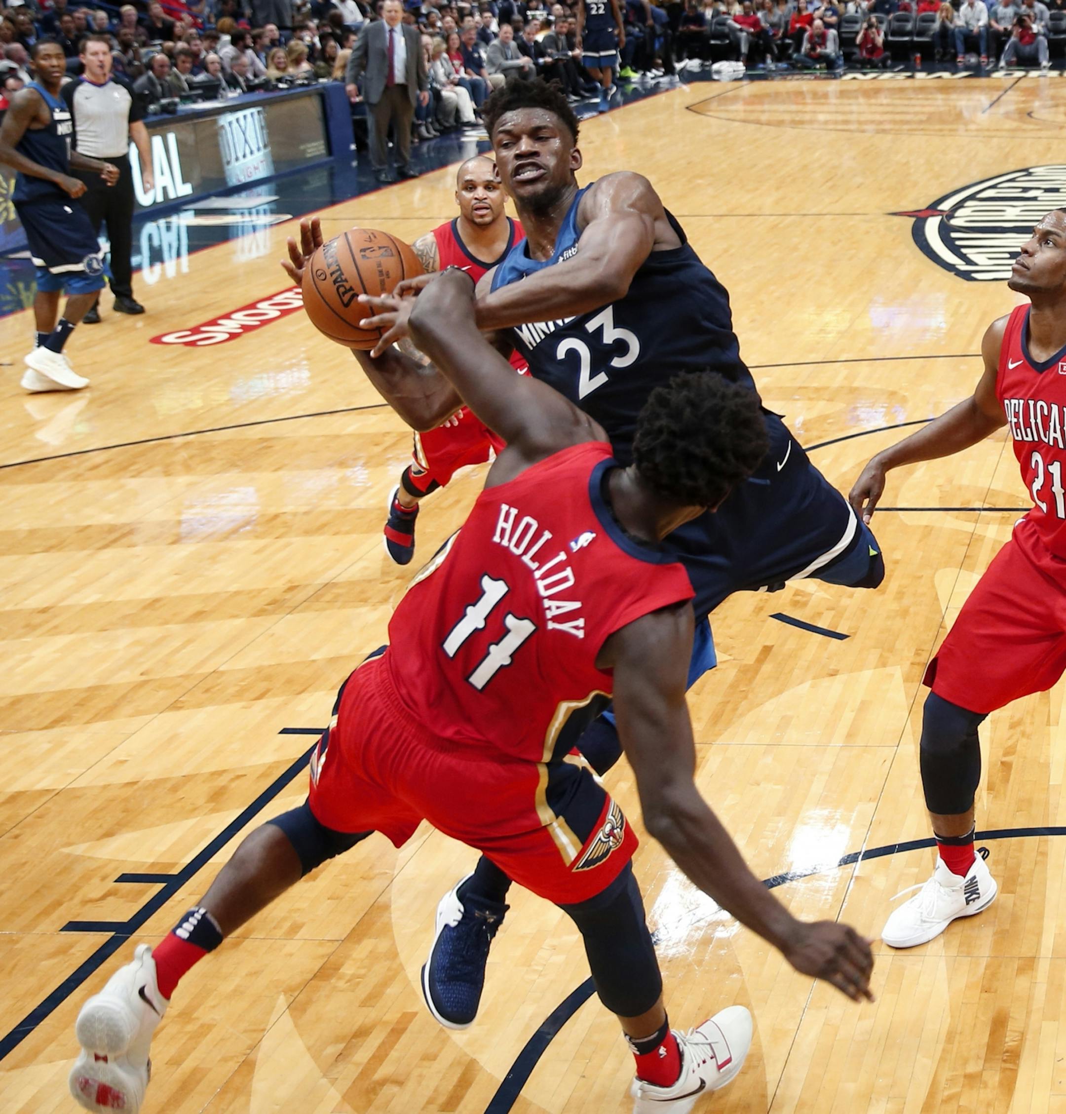 Minnesota Timberwolves guard Jimmy Butler (23) goes to the basket against New Orleans Pelicans guard Jrue Holiday (11) during the second half of an NBA basketball game in New Orleans, Wednesday, Nov. 29, 2017. The Timberwolves won 120-102.