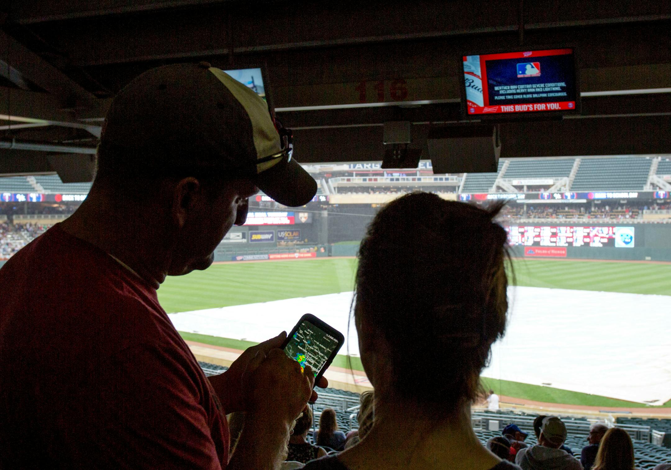 Minnesota Twins fans check a radar app on their phone during a rain delay before a baseball game between the Twins and the Texas Rangers on Saturday, Aug. 5, 2017, in Minneapolis. (AP Photo/Andy Clayton-King)