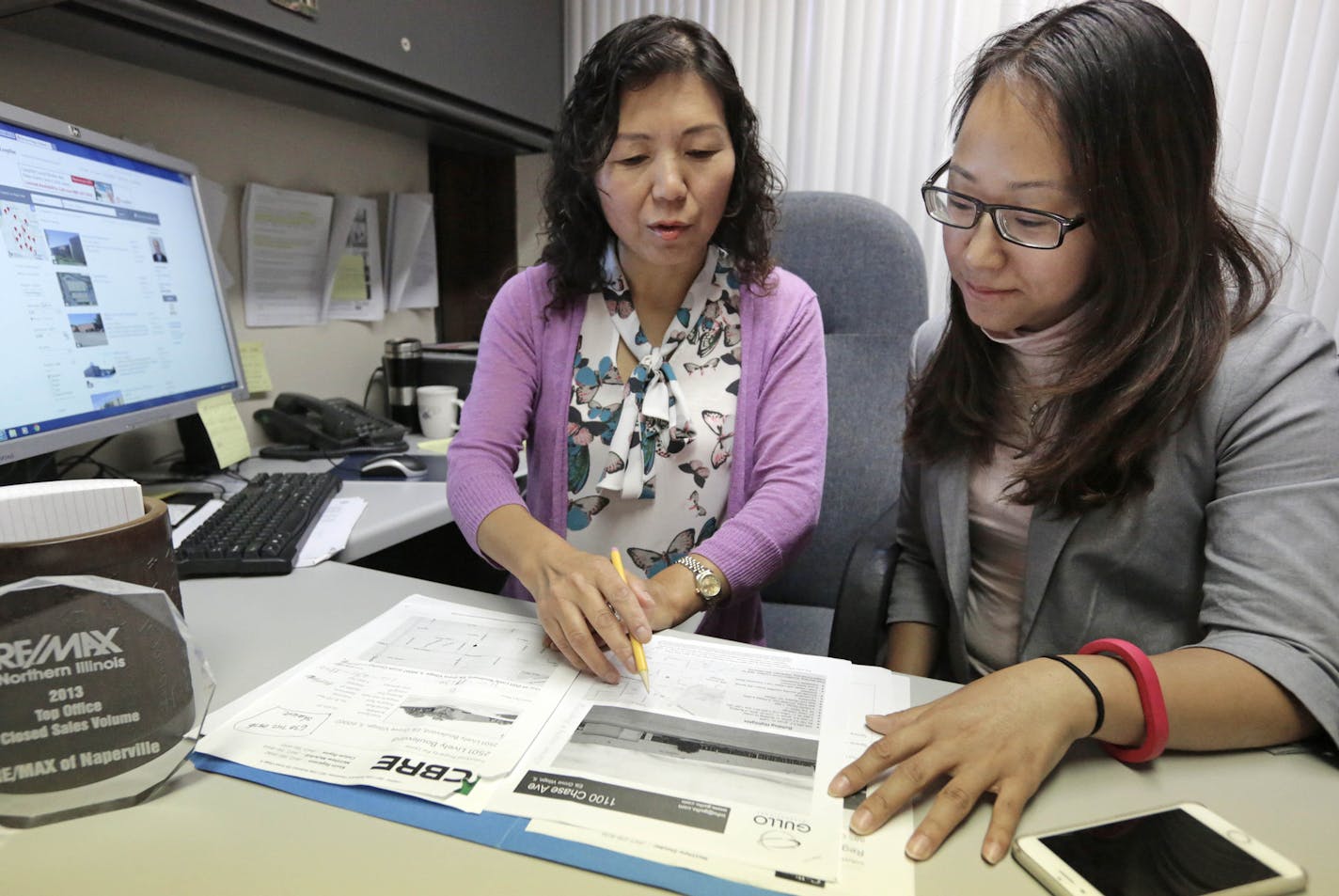 In this Wednesday, Sept. 16, 2015 photo, Shanshan Wu, right, goes over real estate listings with her broker, Lisa Li, in Naperville, Ill. Wu, who already owns three houses back home in China, has spent the last two months in Chicago shopping for a three-bedroom home, and she&#xed;s not done. Chinese have been snapping up U.S. real estate of all kinds, looking for a safer place to put their money than their own slowing economy. (AP Photo/M. Spencer Green) ORG XMIT: NYBZ120