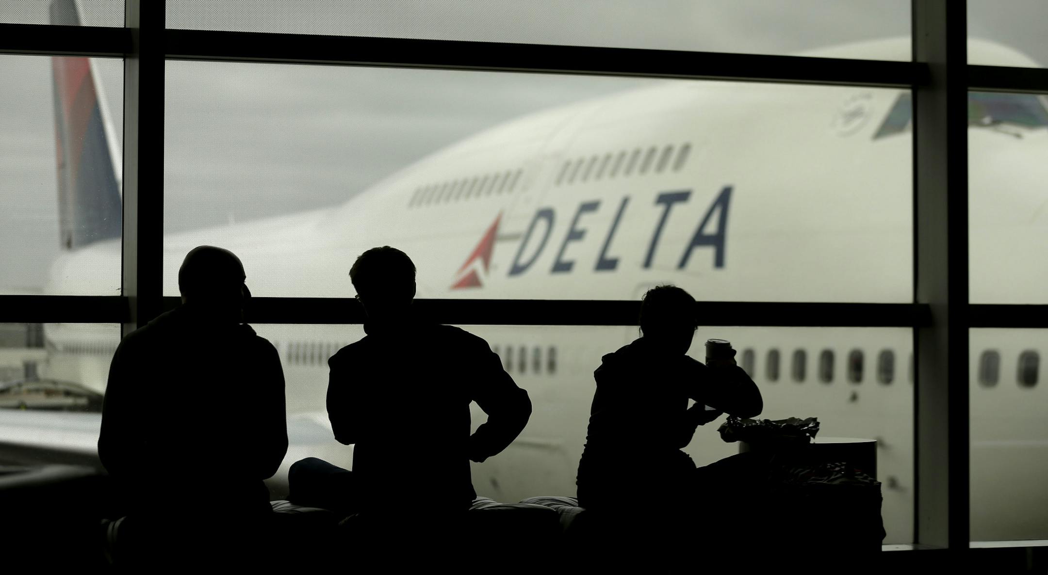 FILE - In this Monday, Oct. 29, 2012, file photo, travelers on Delta Air Lines wait for flights, in Detroit. Delta Air Lines Inc. said Thursday, April 14, 2016, it would drop the fee for U.S. consumers who buy tickets over the phone or at a ticket counter. The phone fee was $25 and the fee for a ticket bought at an airport or other ticket counter was $35. (AP Photo/Charlie Riedel, File)