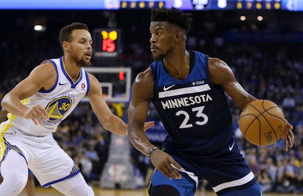 Minnesota Timberwolves' Jimmy Butler, right, drives the ball against Golden State Warriors' Stephen Curry (30) during the first half of an NBA basketb