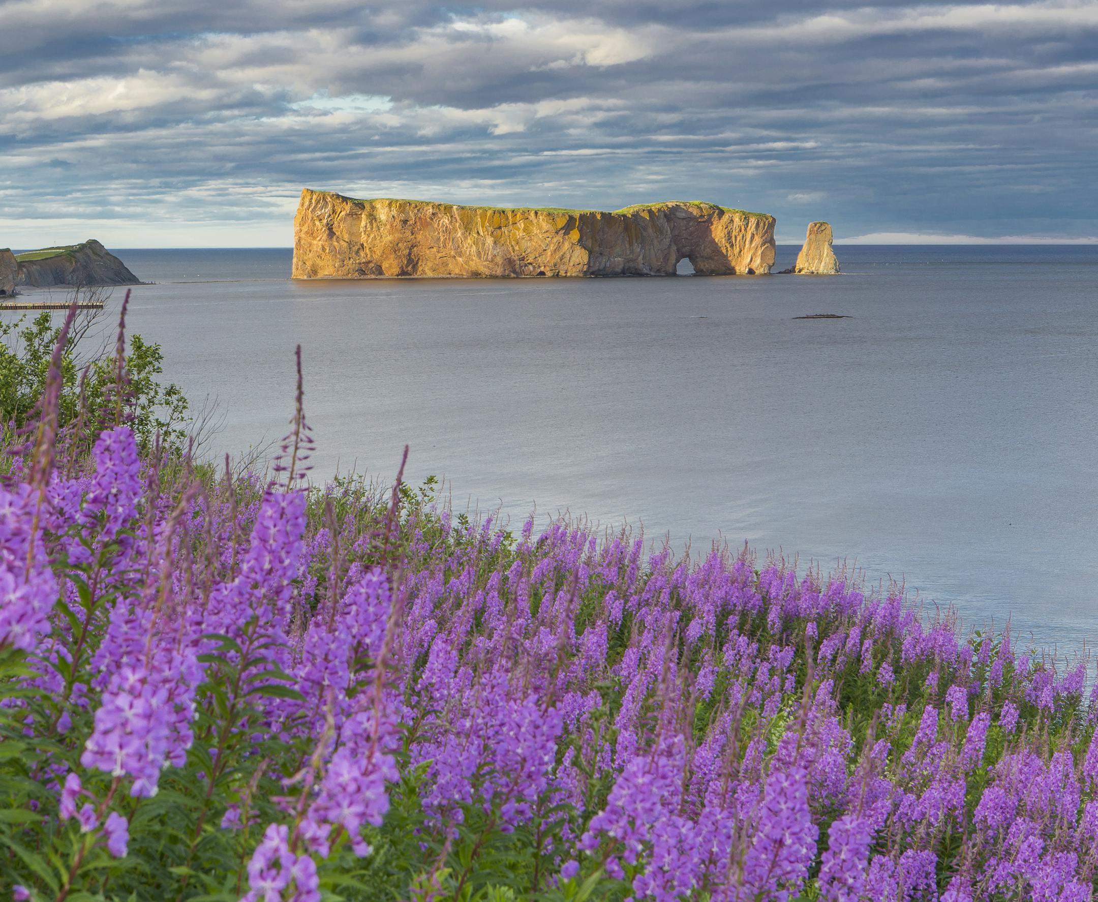 This undated photo provided by QuÈbec Maritime shows Rocher Perce from the Gaspe Peninsula in QuÈbec, Canada. The region offers lighthouses, coastal scenery, whale-watching and attractions like Rocher Perce, a well-known rock formation that rises from the sea with a tunnel-like hole forming an arch beneath it. The loop around the Gaspe is popular with bicyclists and motorcycle riders. (Mathieu Dupuis/QuÈbec Maritime via AP)