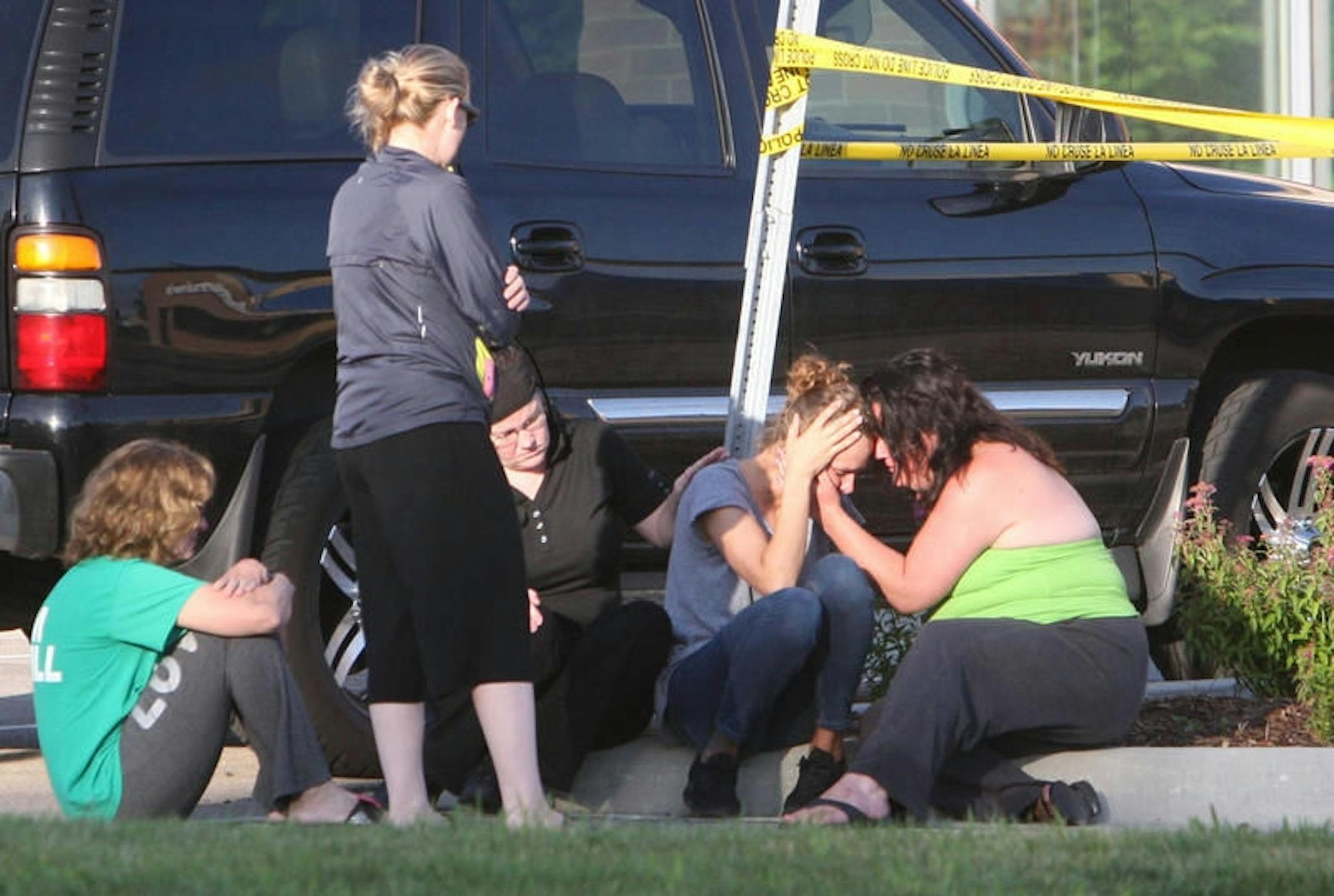 A group of women console each other at the edge of the parking lot of Dominos Pizza on 41st St. Northwest Friday morning in Rochester, MN. where a teenage boy was stabbed to death. Credit: Ken Klotzbach/Rochester Post Bulletin
