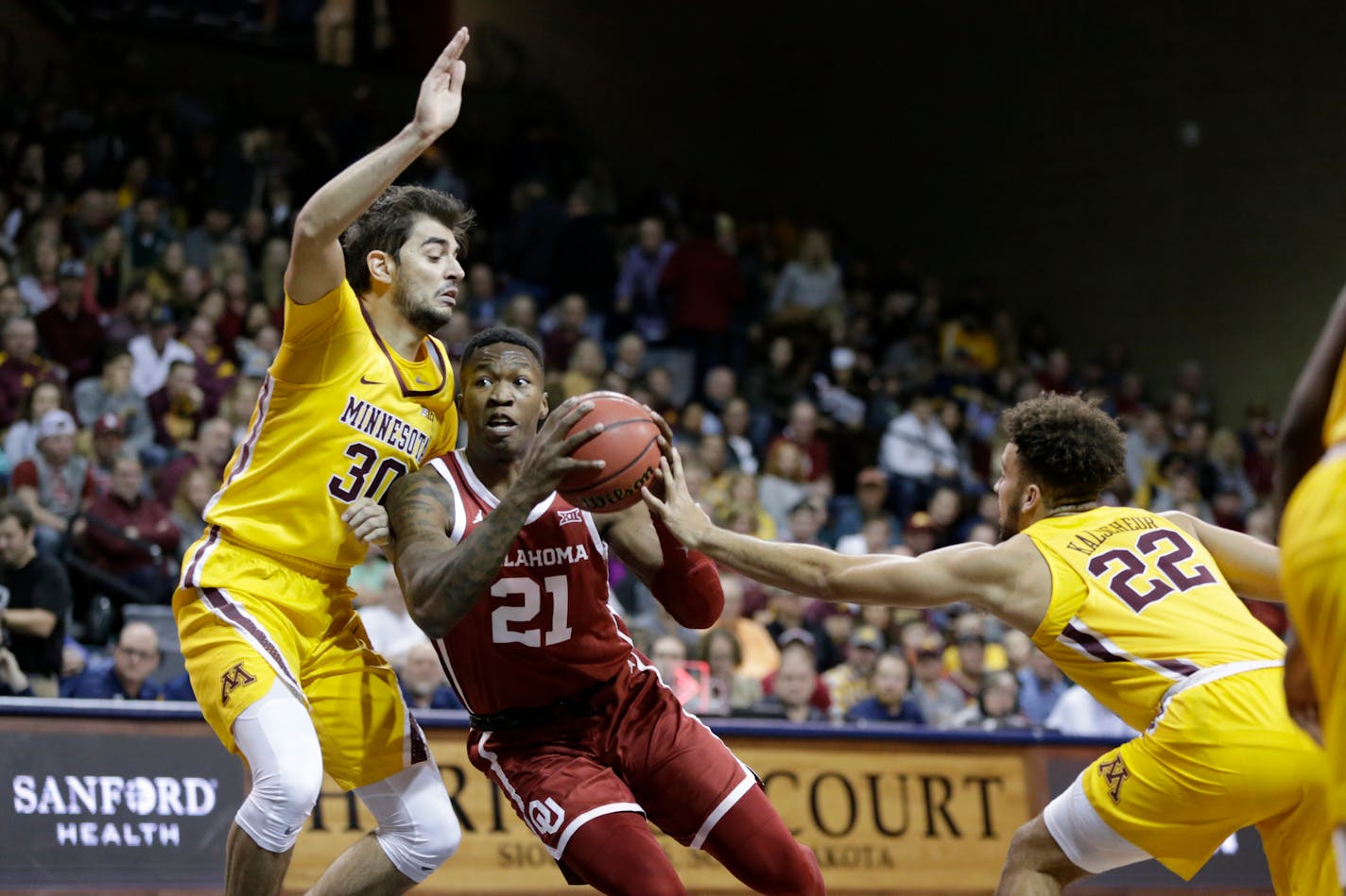 Oklahoma's Kristian Doolittle goes to the basket between Minnesota's Alihan Demir (30) and Gabe Kalscheur (22) during the first half.