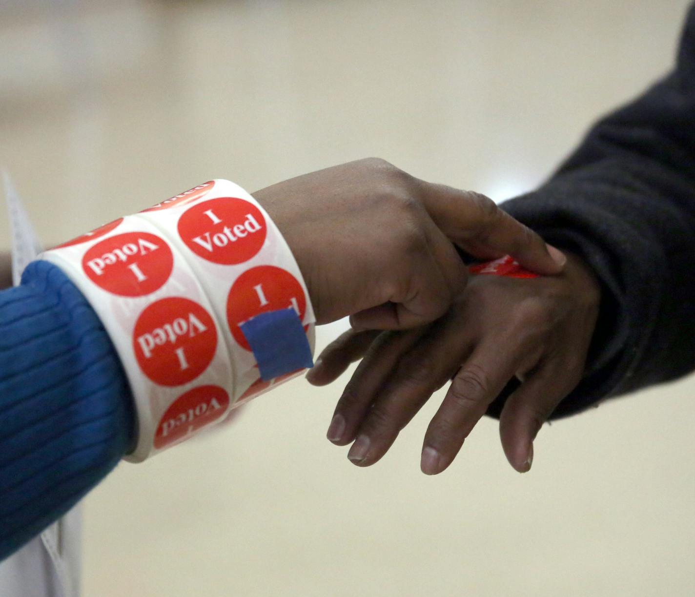 Asst. chief election judge Brenda Bell Brown gives sticker to voter ] Minneapolis, MN 11/05/2013