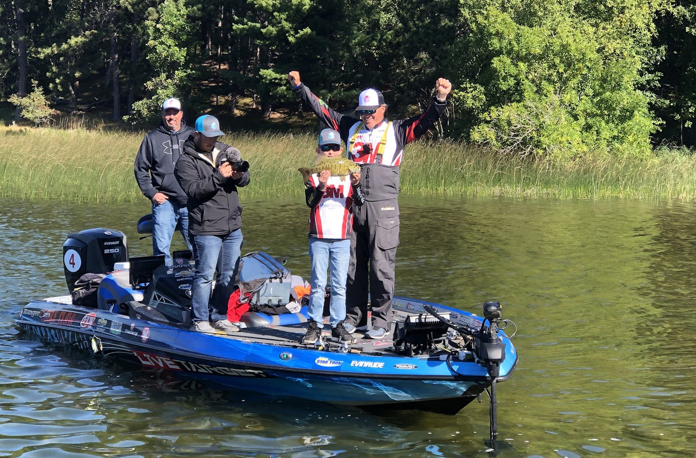 CORRECT CAPTION/USE THIS VERSION. Colby reacted to his catch Wednesday on Mantrap Lake, along with pro angler Scott Martin, right, and Colby's dad, Seth, far left.