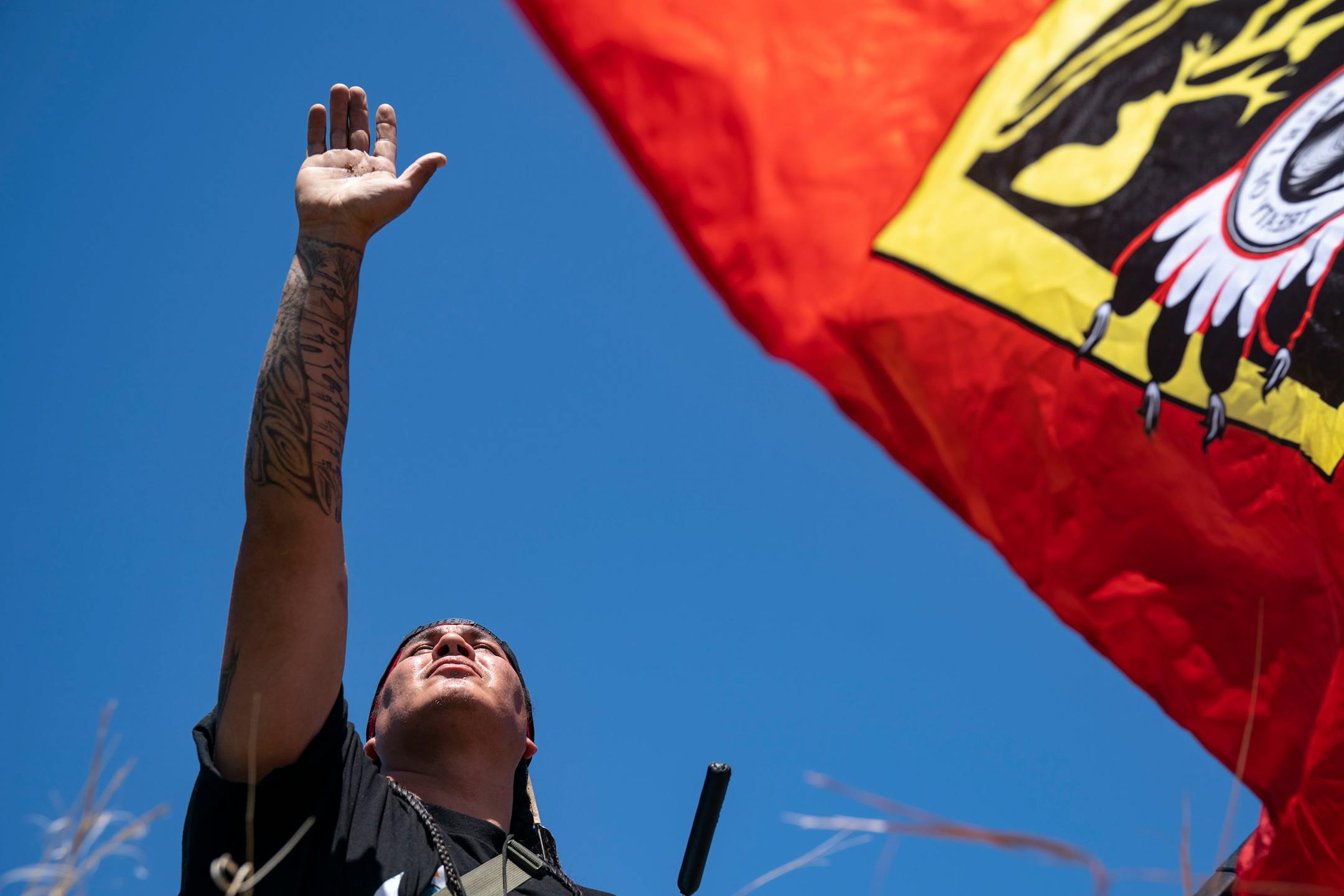 Roy Broncheau aka Walks Through Hail raised his hand to the sky after performing a prayer with tobacco on the bank of the Mississippi River on Monday.