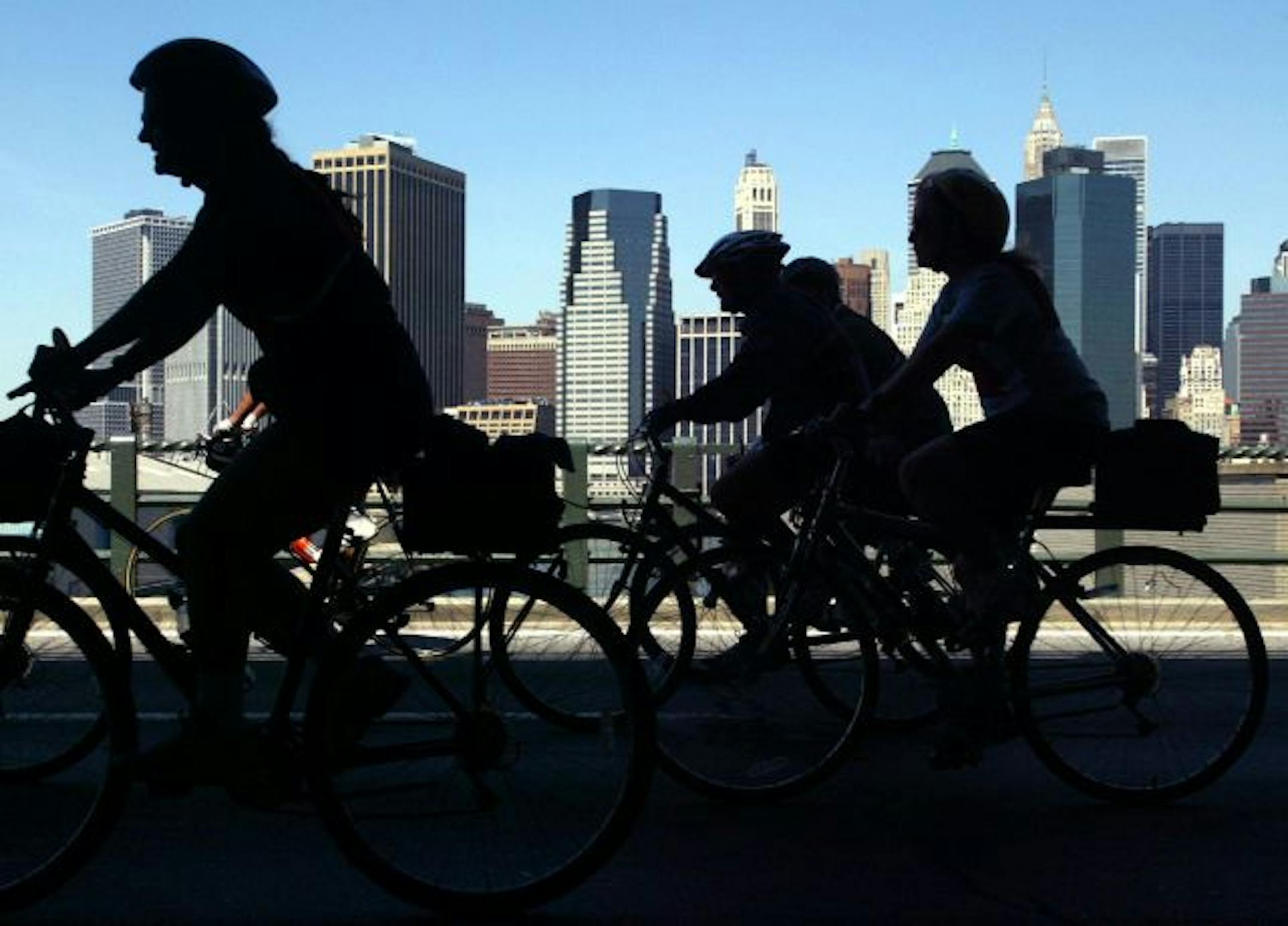 Some of the estimated thirty thousand participants in the 25th annual Bike New York tour pass by a view of the lower Manhattan skyline, in the Brooklyn borough of New York, Sunday, May 5, 2002. Roads are closed down to allow bicyclists to travel the 42 miles through the five boroughs, traffic free.