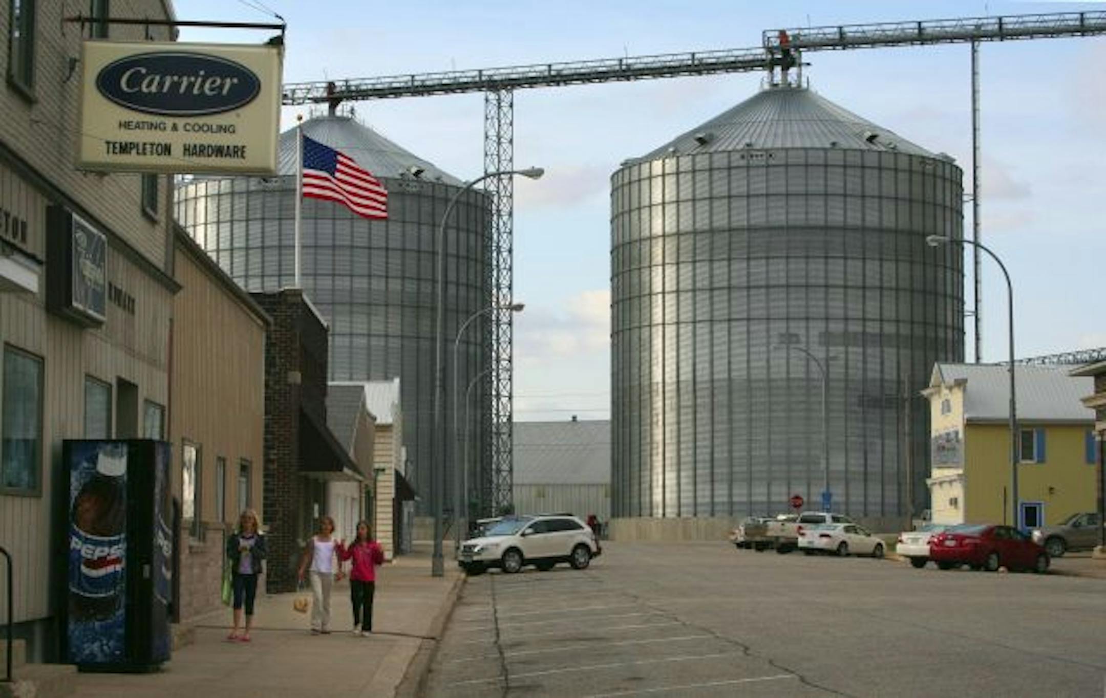 Silo towers over locals as they stroll Main Street in Templeton, Iowa.