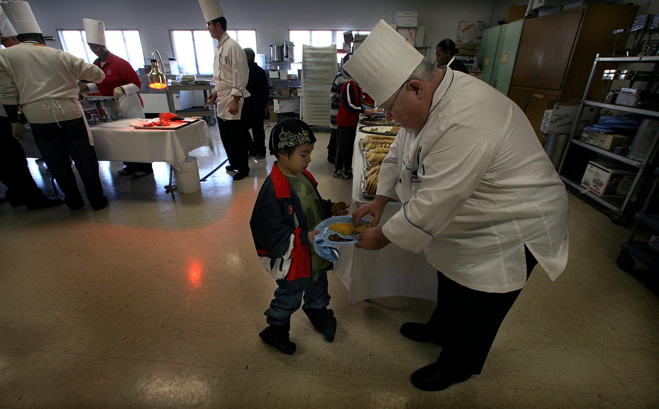 Retired chef Bo Kozak, 64, gave a cookie to Hernan Inamagua, 6, during a holiday dinner at the McKnight Early Childhood Family Development Center in Minneapolis.