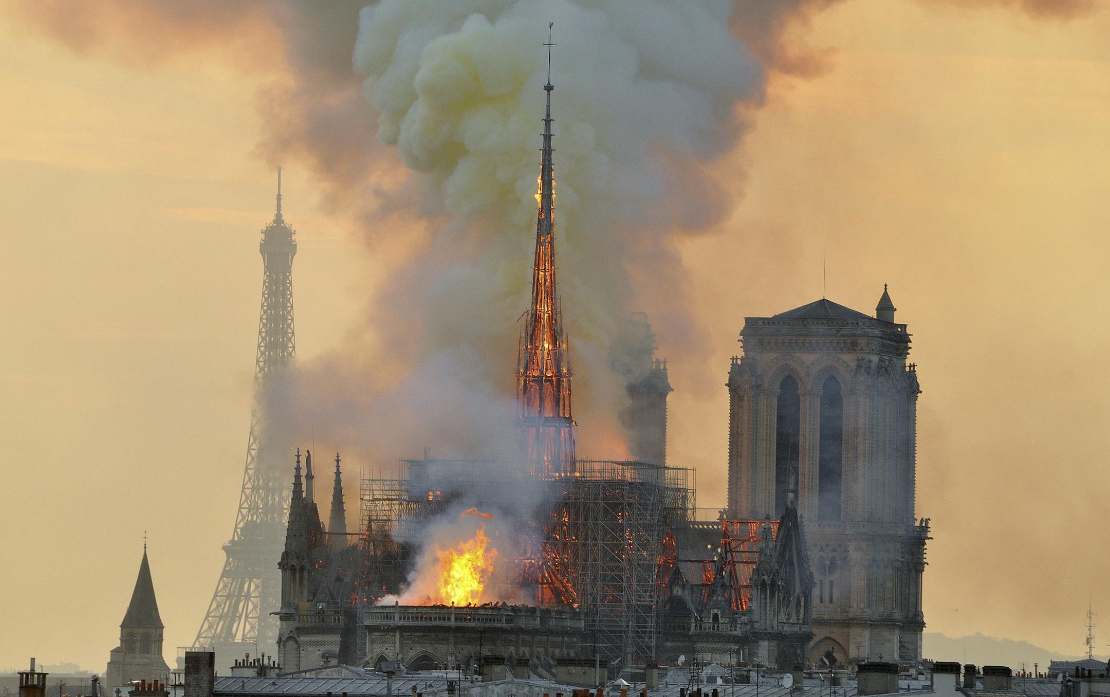In this image made available on Tuesday April 16, 2019 flames and smoke rise from the blaze at Notre Dame cathedral in Paris, Monday, April 15, 2019. An inferno that raged through Notre Dame Cathedral for more than 12 hours destroyed its spire and its roof but spared its twin medieval bell towers, and a frantic rescue effort saved the monument's "most precious treasures," including the Crown of Thorns purportedly worn by Jesus, officials said Tuesday. (AP Photo/Thierry Mallet) ORG XMIT: TH132