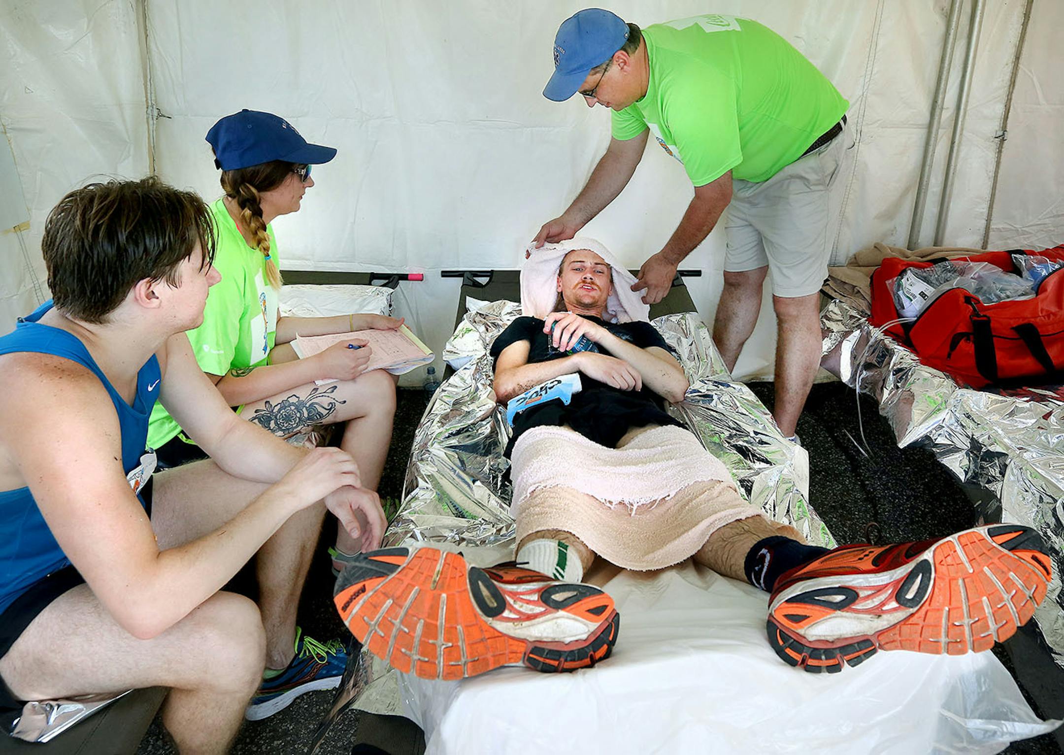Spencer Grimes of the Twin Cities (center) gets medical care after he suffered from overheating during the Grandmas Marathon race Saturday. He was assisted by Amanda Chapman (left), Emergency Medical Responder, and Troy Maly, an Emergency Medical Technician. At left is Grimes' friend and runner Nathan Flynn, also of the Twin Cities.