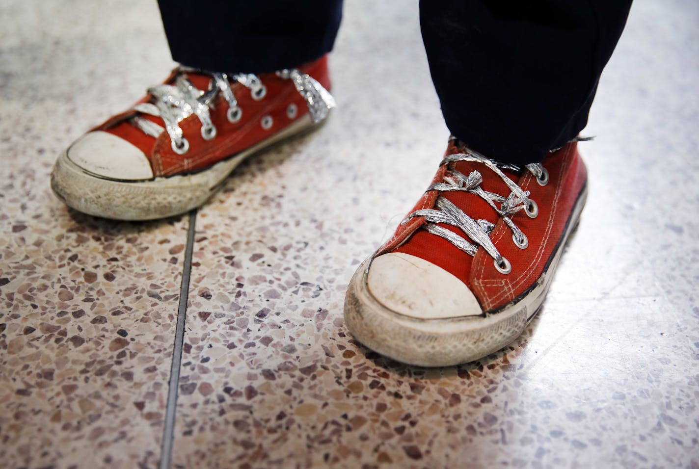 CORRECTS SHOELACE MATERIAL TO ALUMINUM FOIL-LIKE MATERIAL, NOT ALUMINUM FOIL - An immigrant child fleeing Central America uses makeshift shoelaces crafted from the aluminum foil-like material from blankets authorities give migrants for warmth, after the cloth ones were confiscated by the U.S. Border Patrol, in downtown McAllen, Texas, Sunday, June 24, 2018. Immigrants arrived on a government bus at the Central Station bus terminal. From there the families were gathered up by the Catholic Chariti