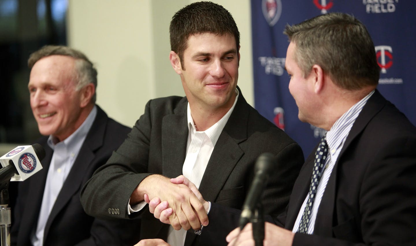 Minnesota Twins catcher Joe Mauer, center, shakes hands with Twins general manager Bill Smith, right, after signing a contract as Mauer's agent Ron Shapiro, left, looks on during a news conference at the team's training facility in Fort Myers, Fla., Monday, March 22, 2010. Mauer agreed to an eight-year, $184 million contract extension to stay with the Twins. (AP Photo/Steven Senne) ORG XMIT: MIN2014022419592350